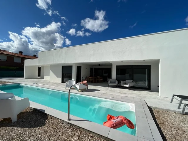 Vivienda de fachada blanca con porche abierto junto a una piscina